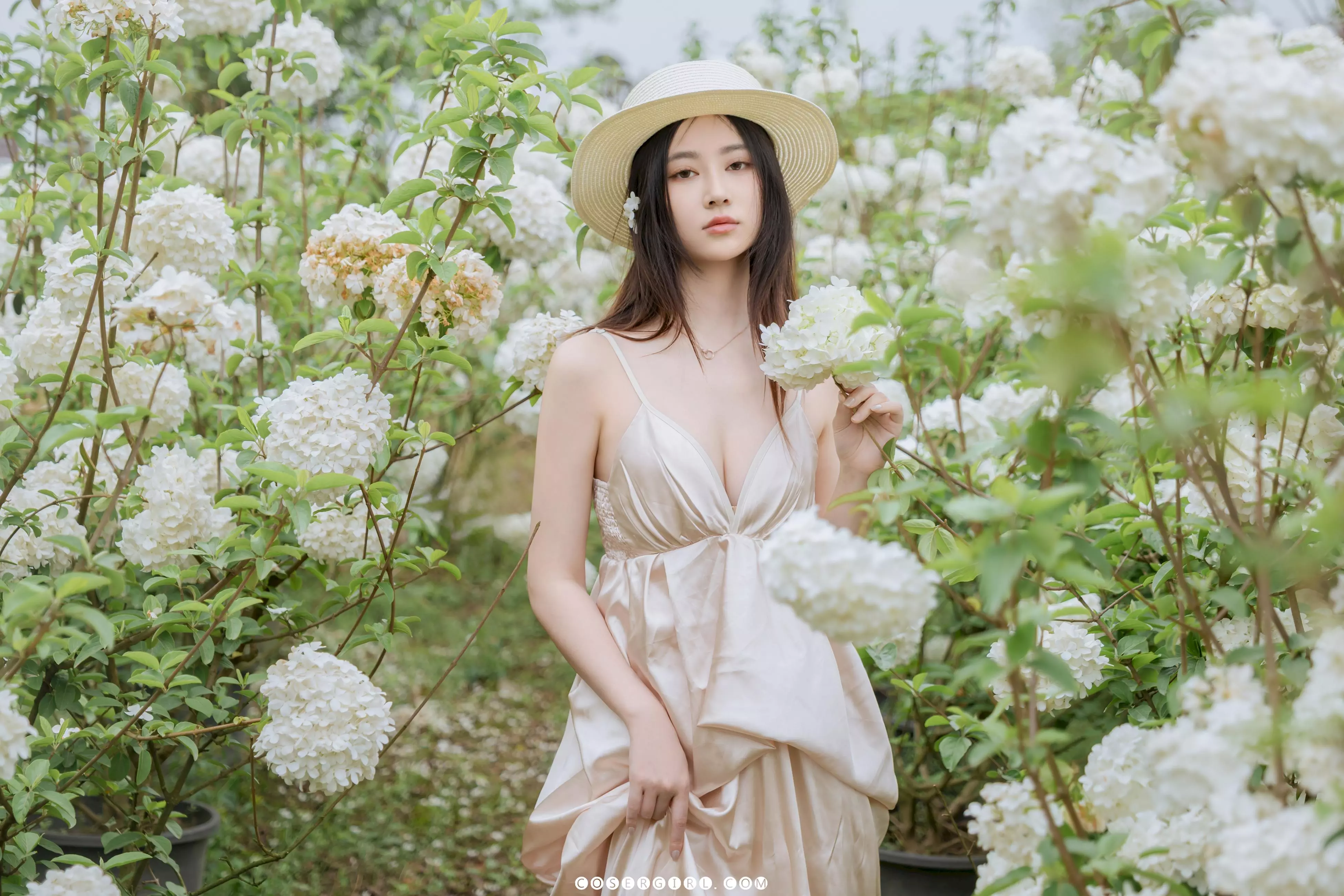 年年双手捧着一簇木绣球花,闭着眼睛面带微笑地感受花香
