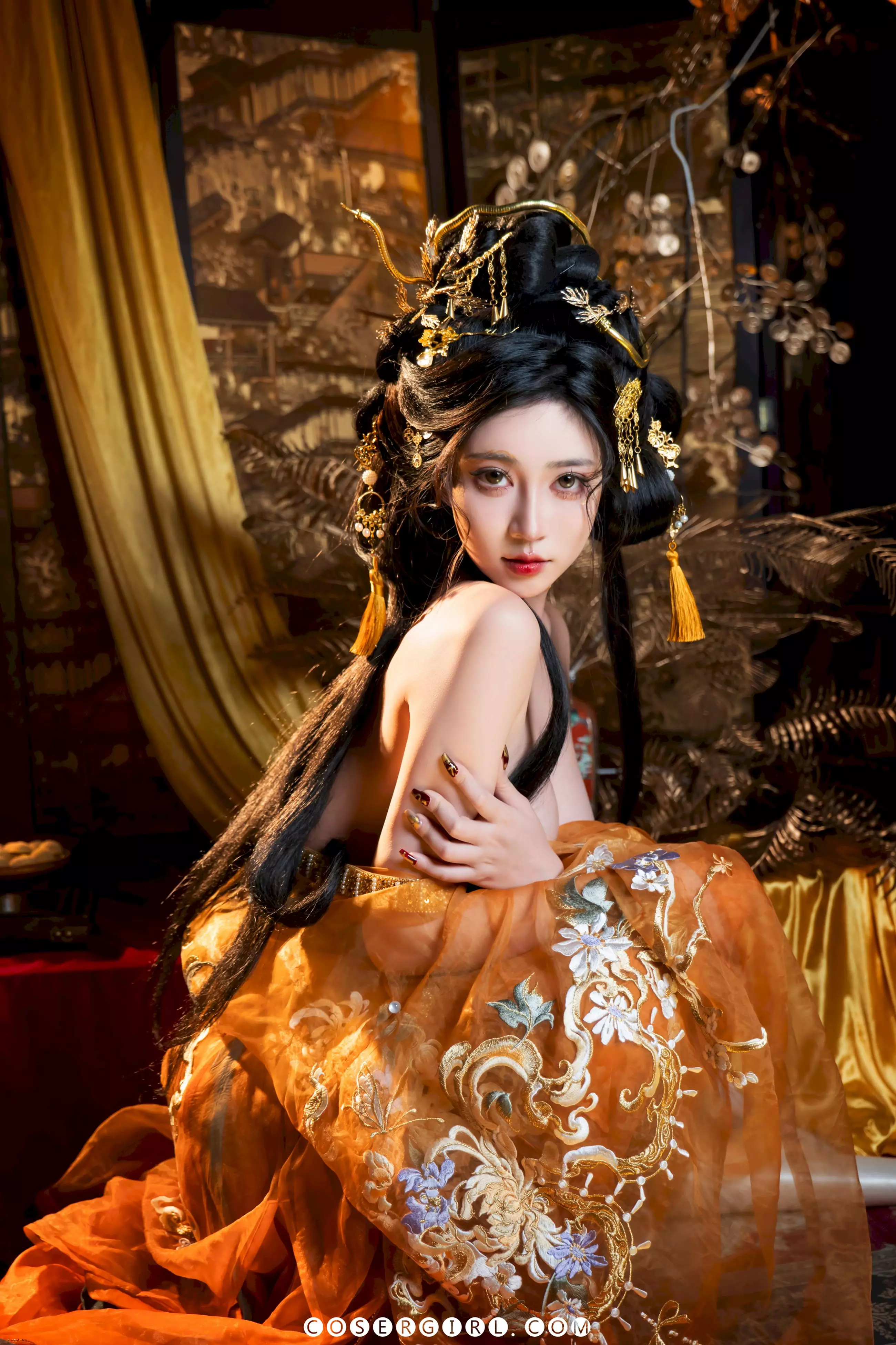 Coser年年身穿金色刺绣抹胸裙,头戴华丽金蛇发簪,侧身坐在宝座上回眸凝视,眼神充满故事感。