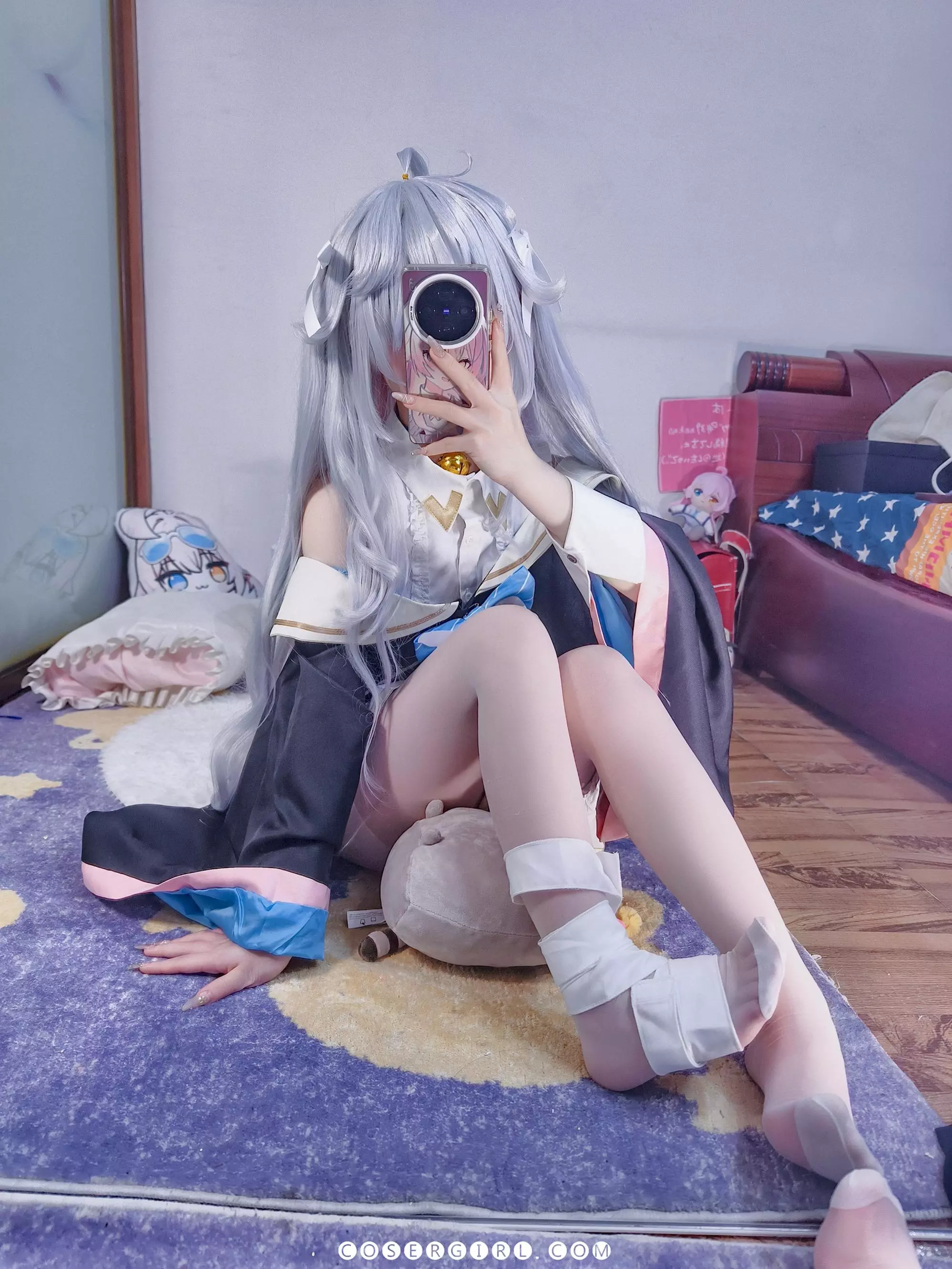 ran3扮演的神乐七奈双腿并拢坐在地毯上,一个戴着生日帽的灰色玩偶被夹在她的脚中间,视角非常独特。