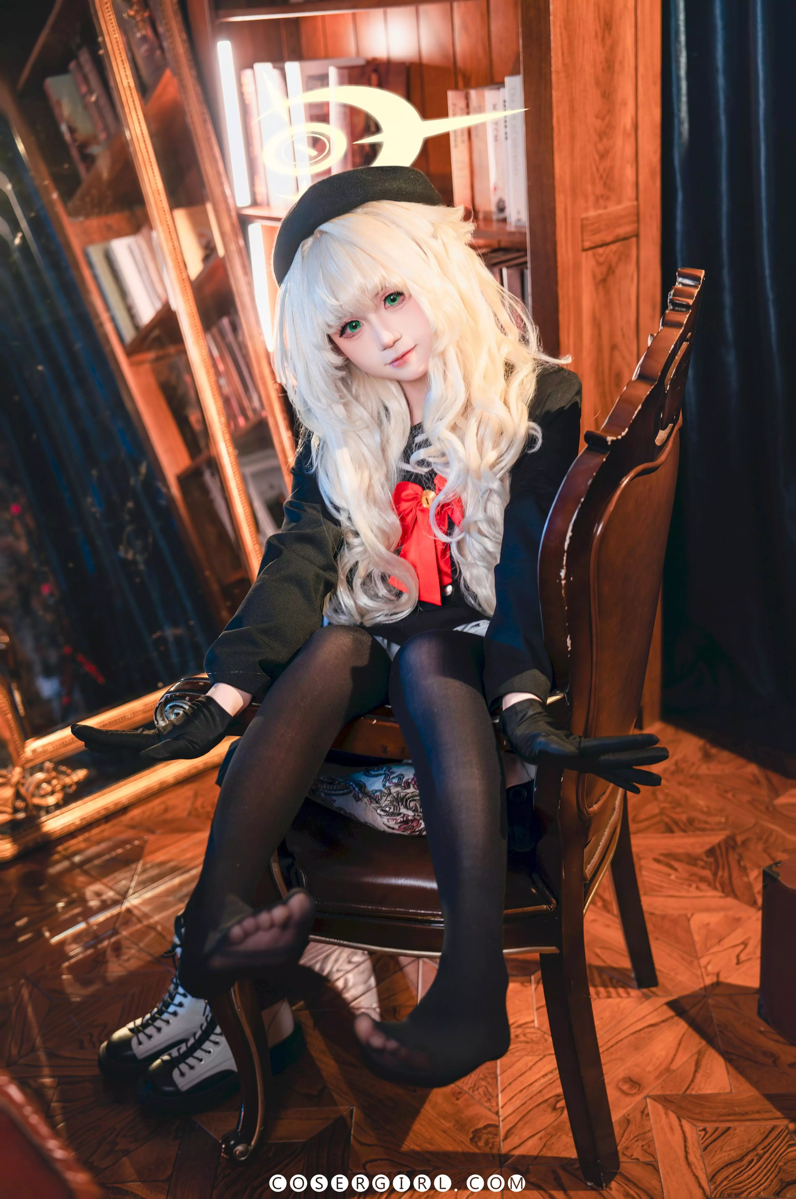 ran3扮演的笑面教授坐在椅子上,将穿着白色厚底靴的双脚翘在桌子边缘,手持手杖,眼神俏皮地看着镜头。