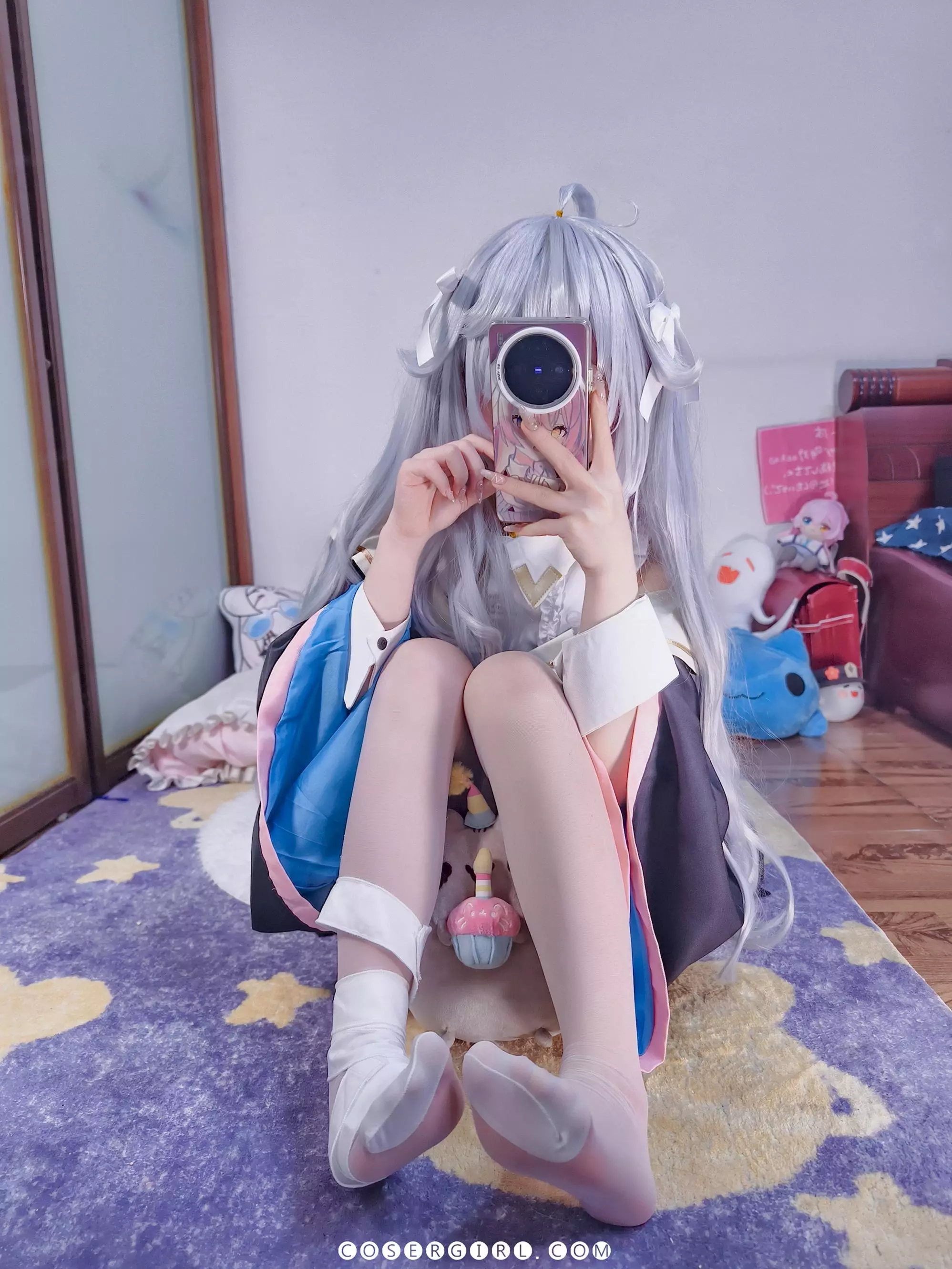 ran3扮演的神乐七奈坐在地毯上,双腿张开,她一手拿着零食,另一只手扶着地,姿态十分放松自然。