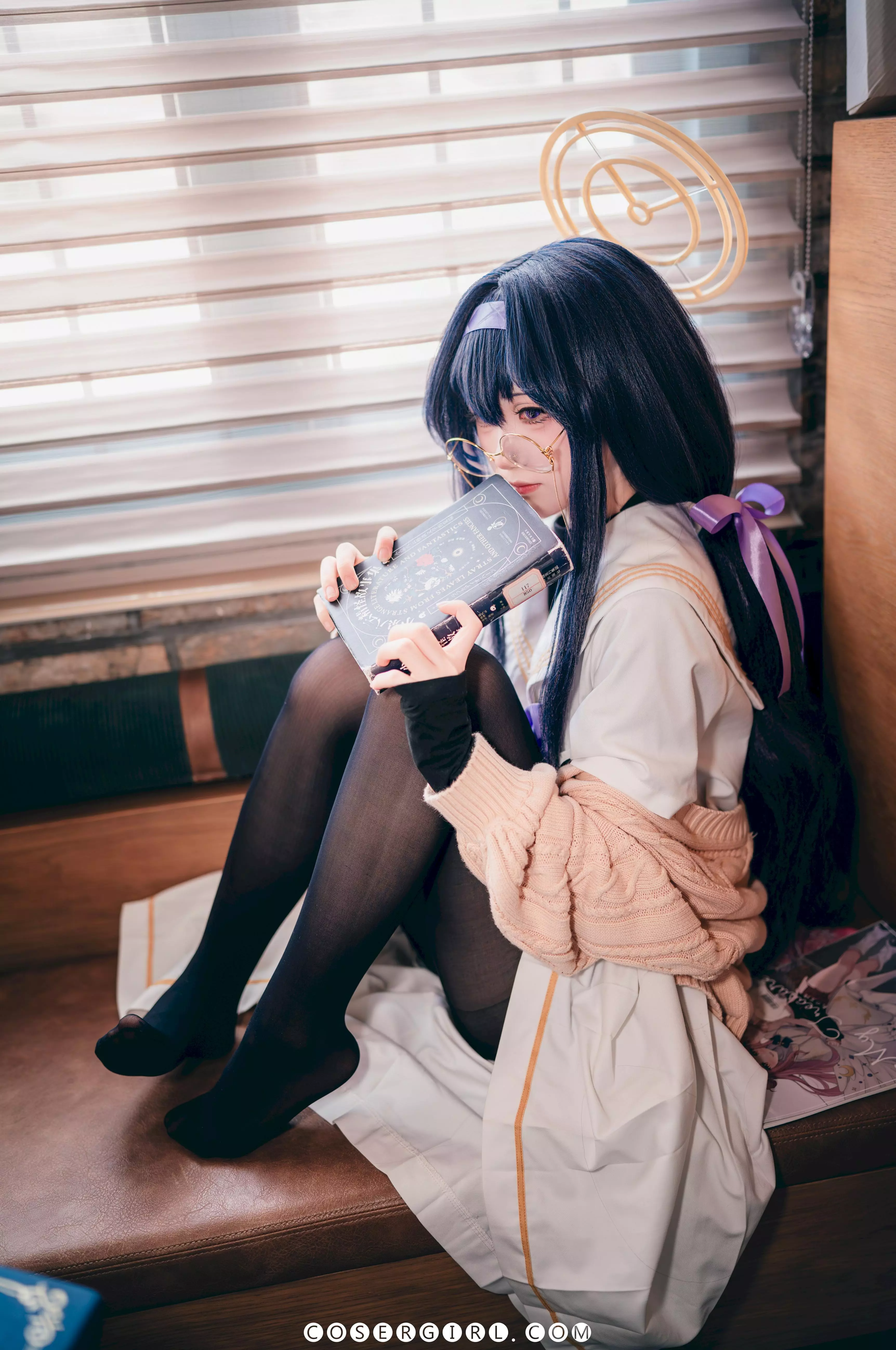 ran3扮演的古关忧坐在沙发上,身体微微前倾,怀里抱着巨大的霰弹枪,专注地看着前方。