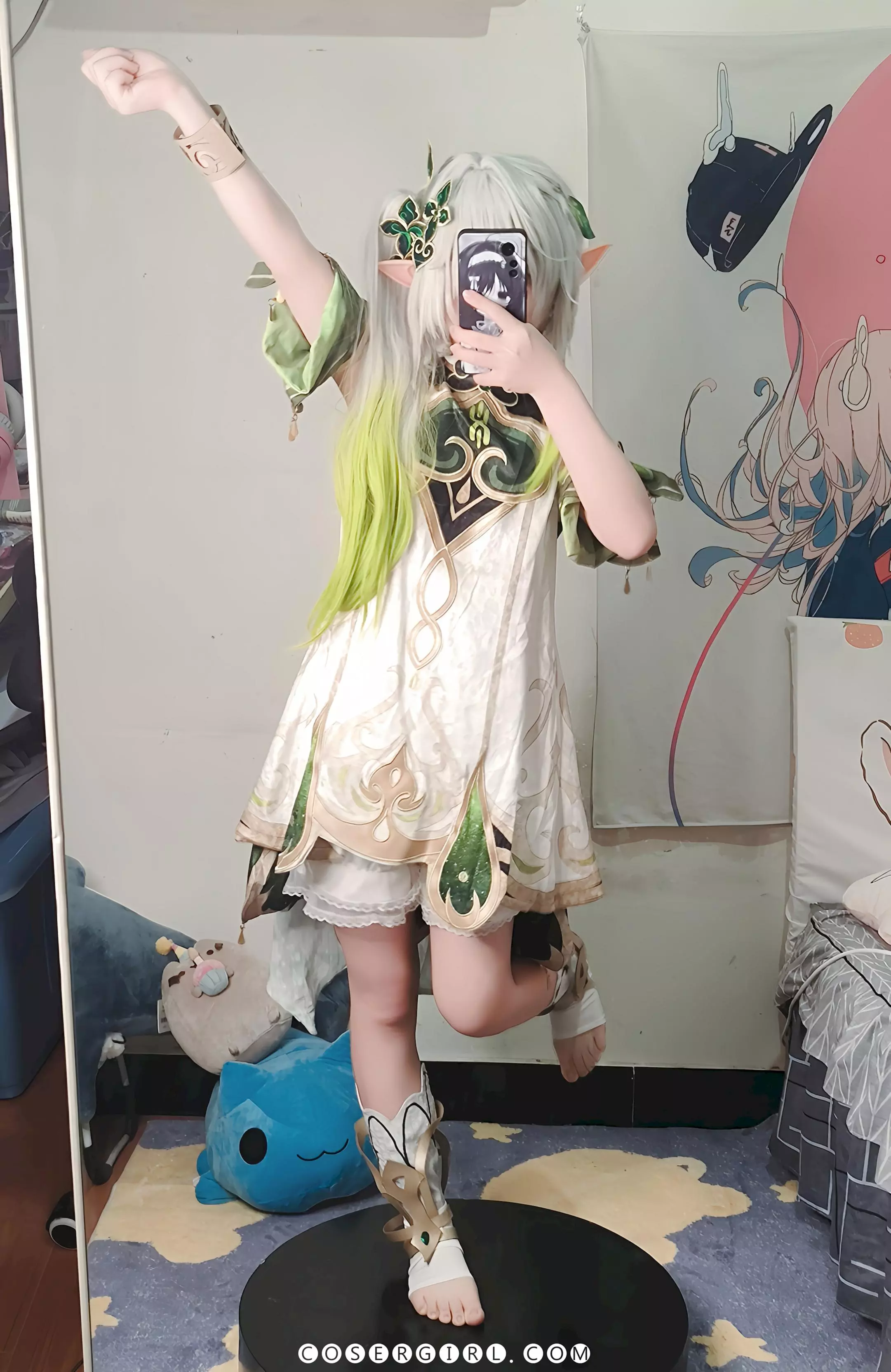 ran3扮演的纳西妲站在黑色圆盘上,单手举高做出胜利手势,对着镜子自拍。