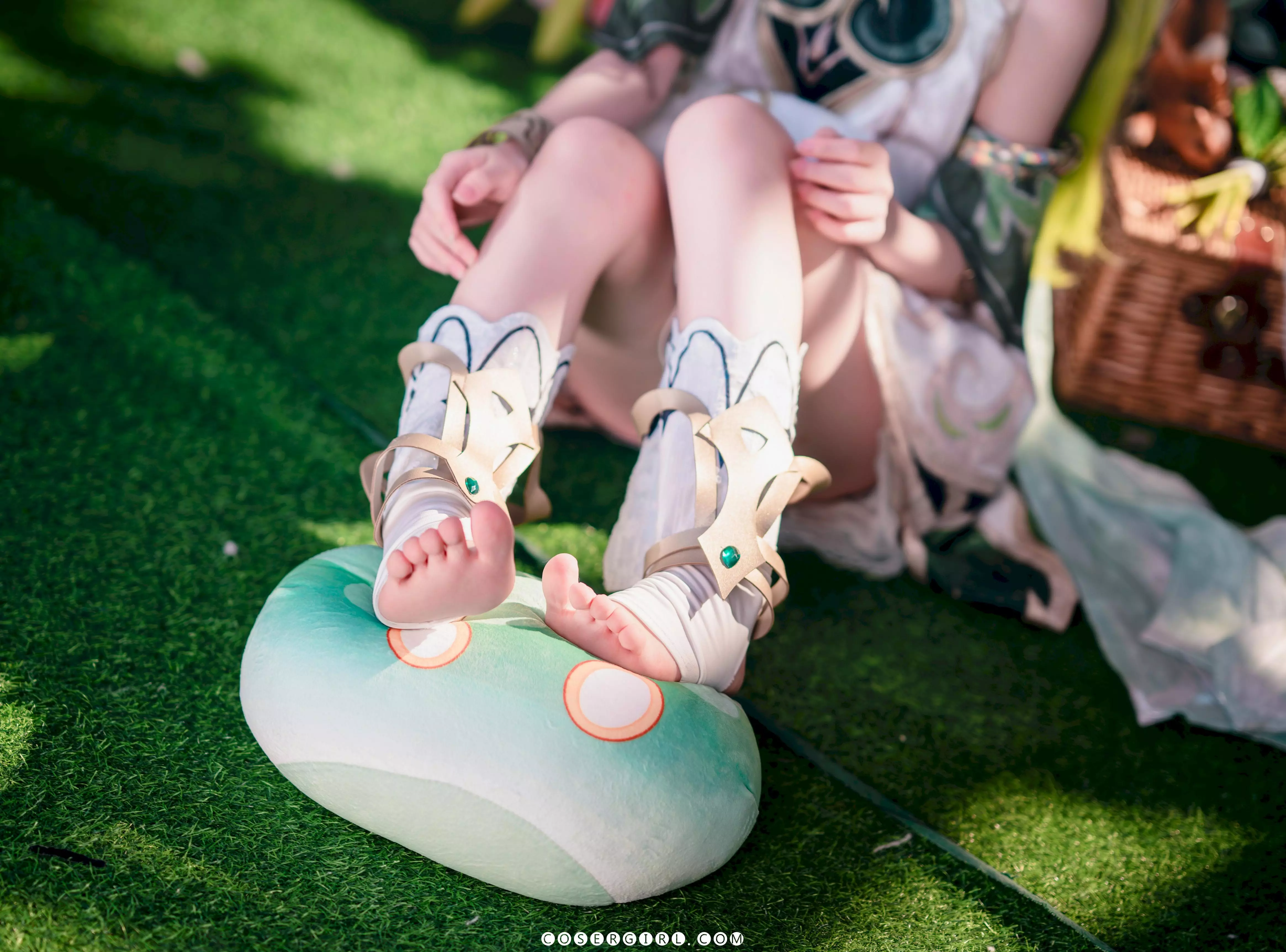 ran3扮演的纳西妲侧身站立在充满鲜花和甜点的场景中,她回头看向镜头,银绿色的长发飘动,姿态优雅。