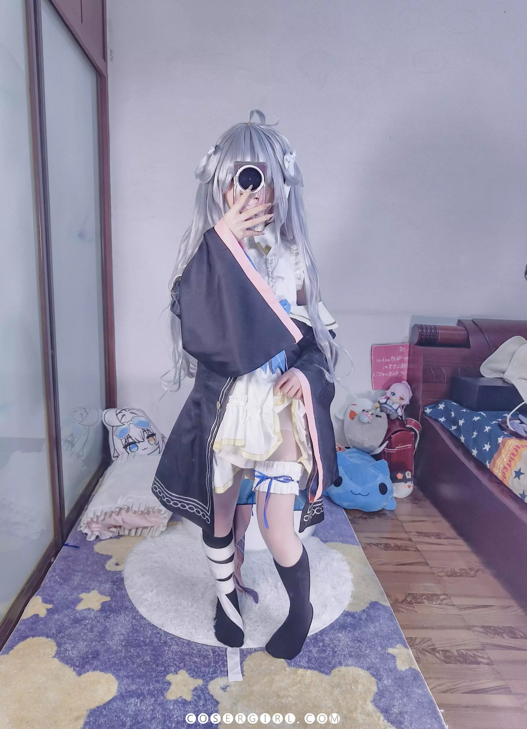 ran3扮演的神乐七奈坐在地毯上对镜自拍,她的右脚踝缠着白色绷带,与另一只脚的黑色袜子形成对比,穿着半透明的白色丝袜。