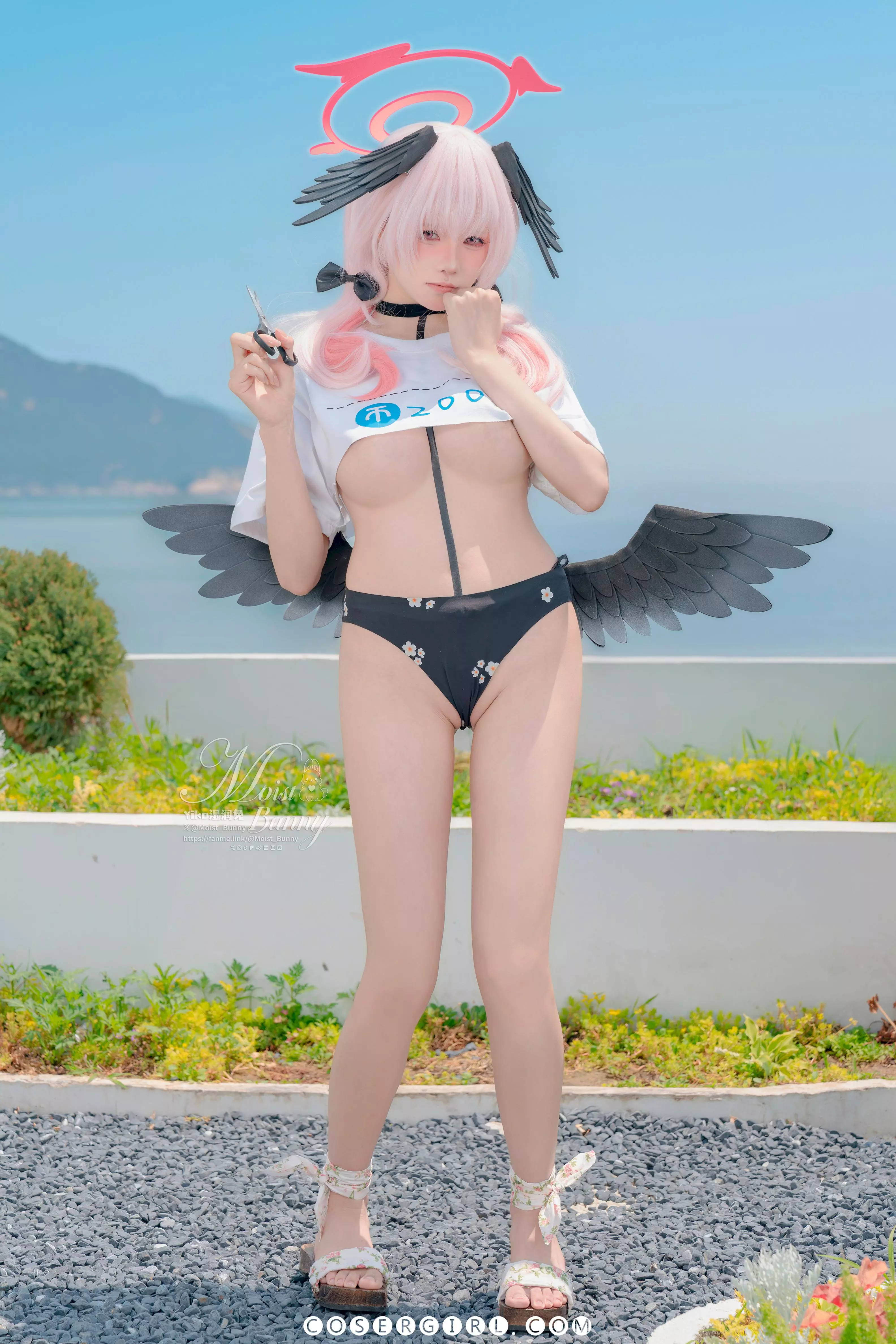 黏黏团子兔cos的下江小春全身站立在碎石地上，她穿着白色绑带凉鞋，白色T恤和印花泳裤，背后是蓝天大海。