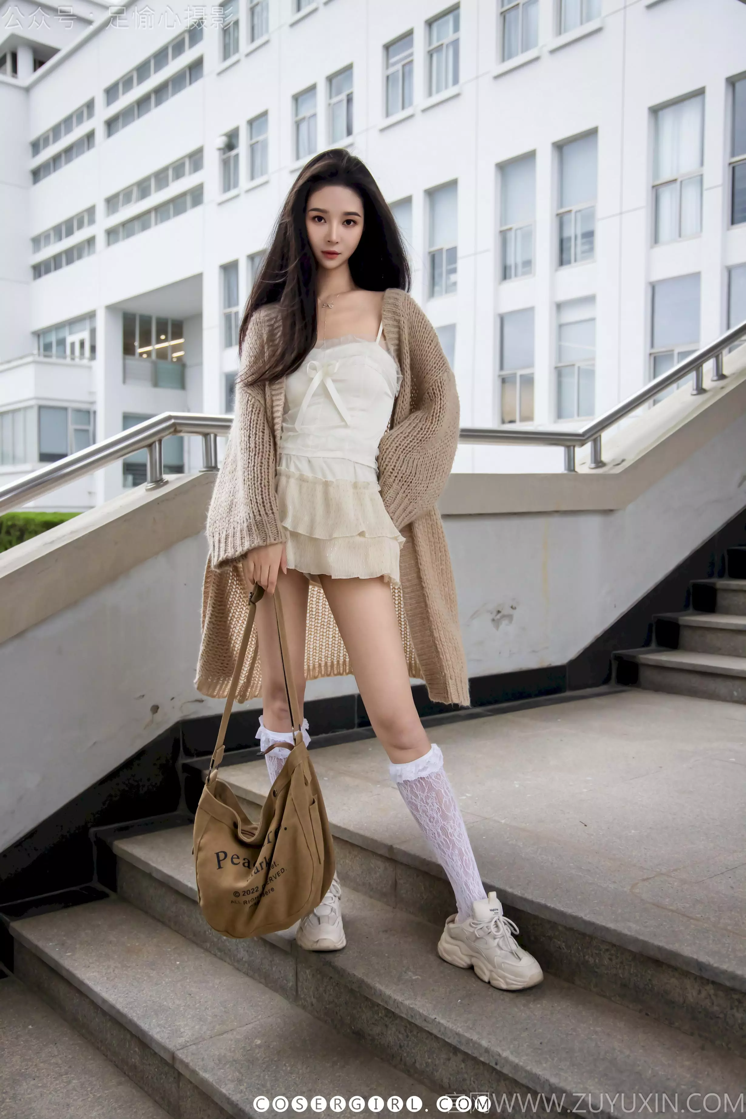 足愉心站在讲台旁，一手扶着讲台，一手拿着麦克风靠近嘴边，眼神专注地看着前方。