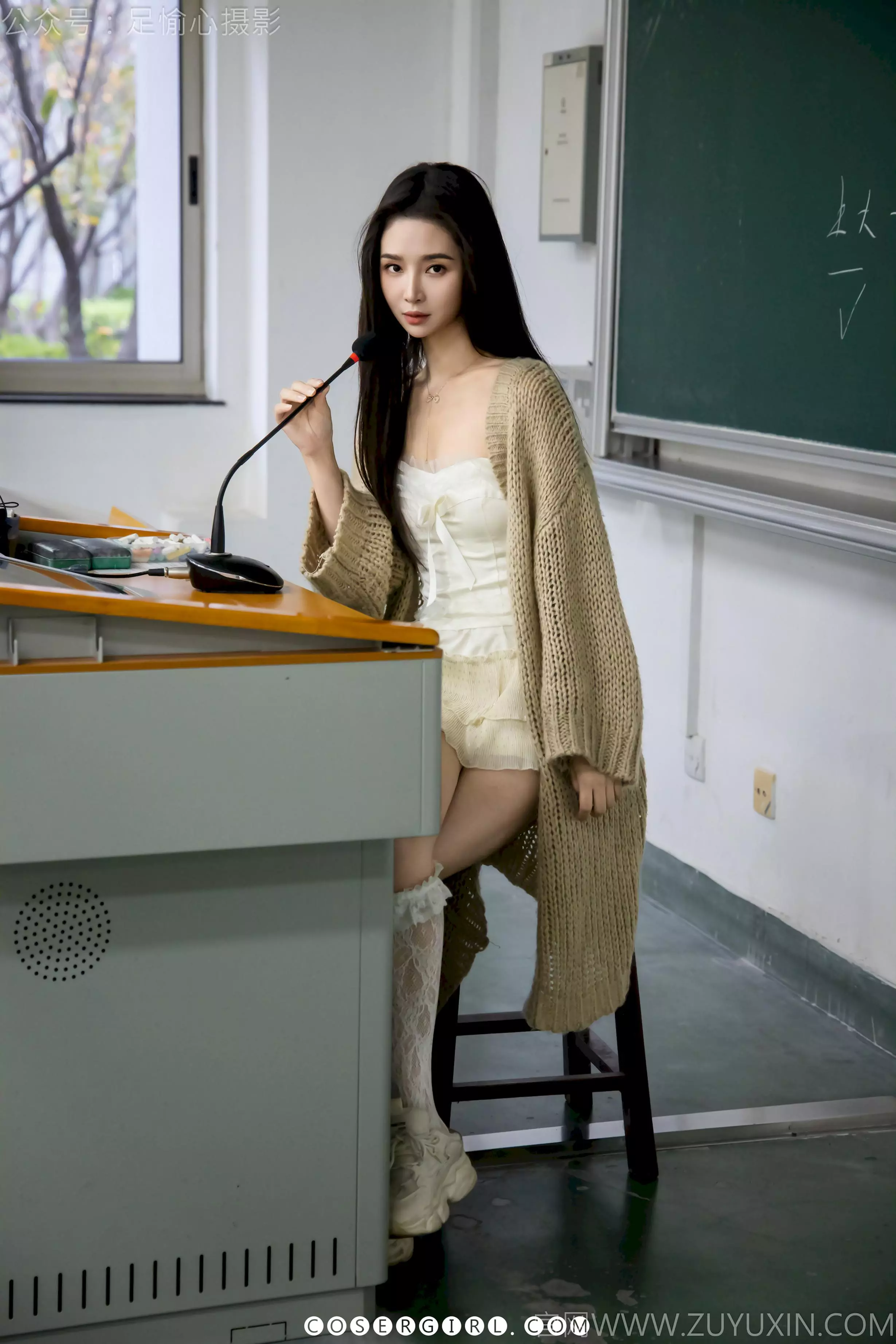足愉心坐在课桌上，褪下一只白色蕾丝袜，露出光洁的脚丫，另一只袜子还穿在腿上。